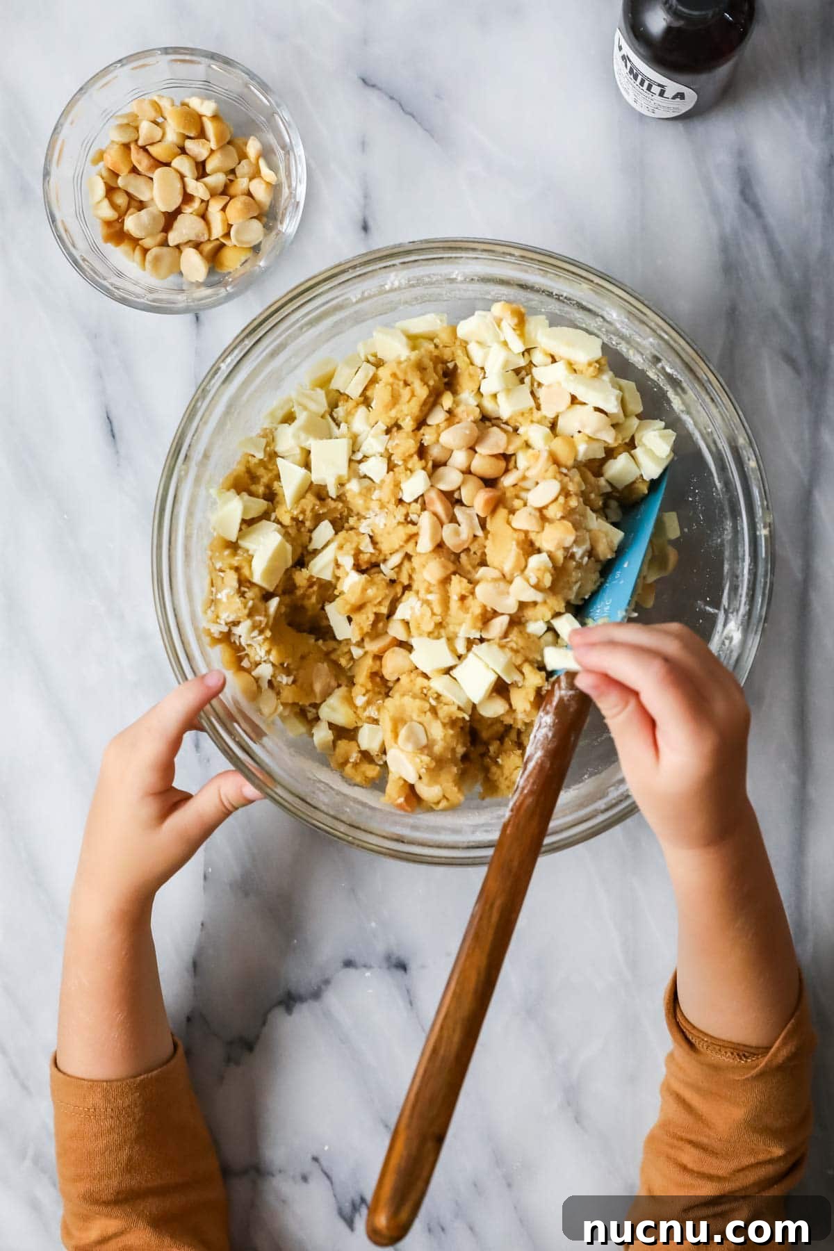 White Chocolate Macadamia Nut Cookies Recipe for Chewy, Crisp Bites 4 Overhead view of a bowl of cookie dough topped with white chocolate chunks and macadamia nuts.