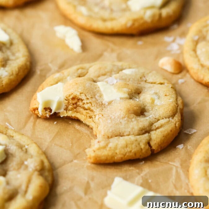 White Chocolate Macadamia Nut Cookies Recipe for Chewy, Crisp Bites 7 Close-up view of a white chocolate macadamia nut cookie missing a bite.