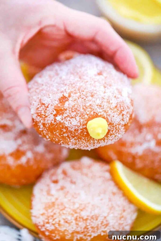 holding a stacked lemon curd filled donut
