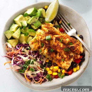 Baja-Style Fish Taco Bowls with Cilantro Lime Slaw 12 A bowl filled with a pan fried cod over corn and bean salsa with slaw and avocado.