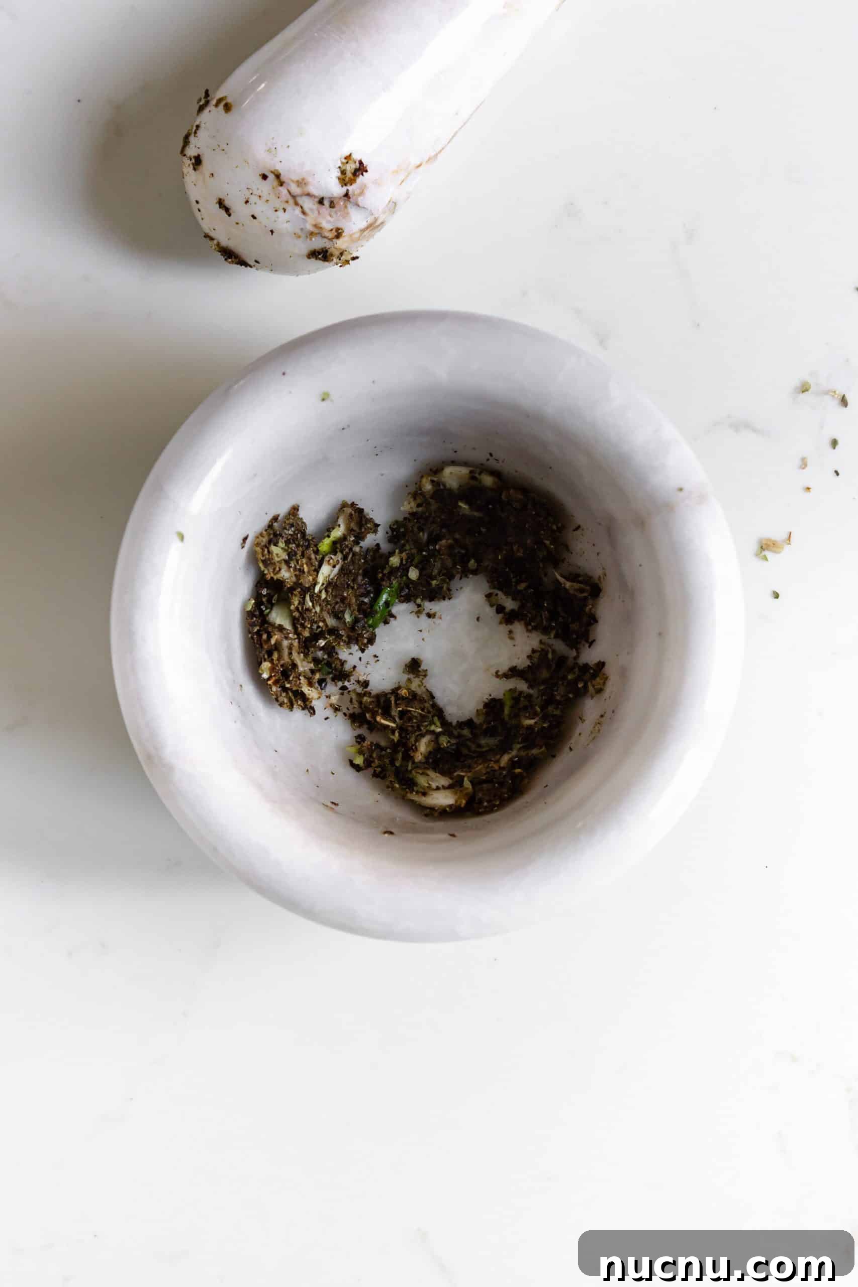 seasonings and herbs ground together in a small white mortar