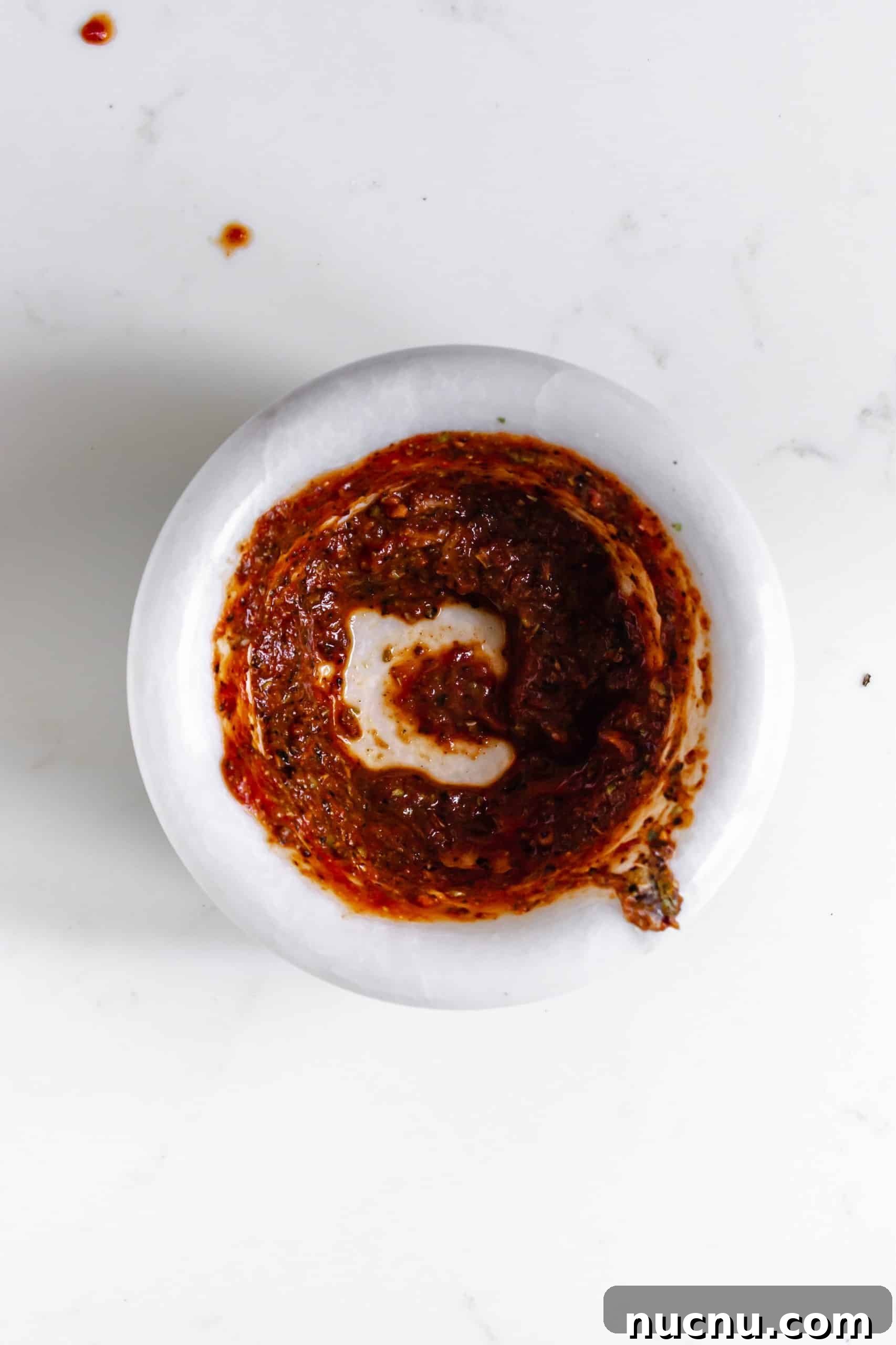 adobo sauce ingredients crushed in a small white mortar