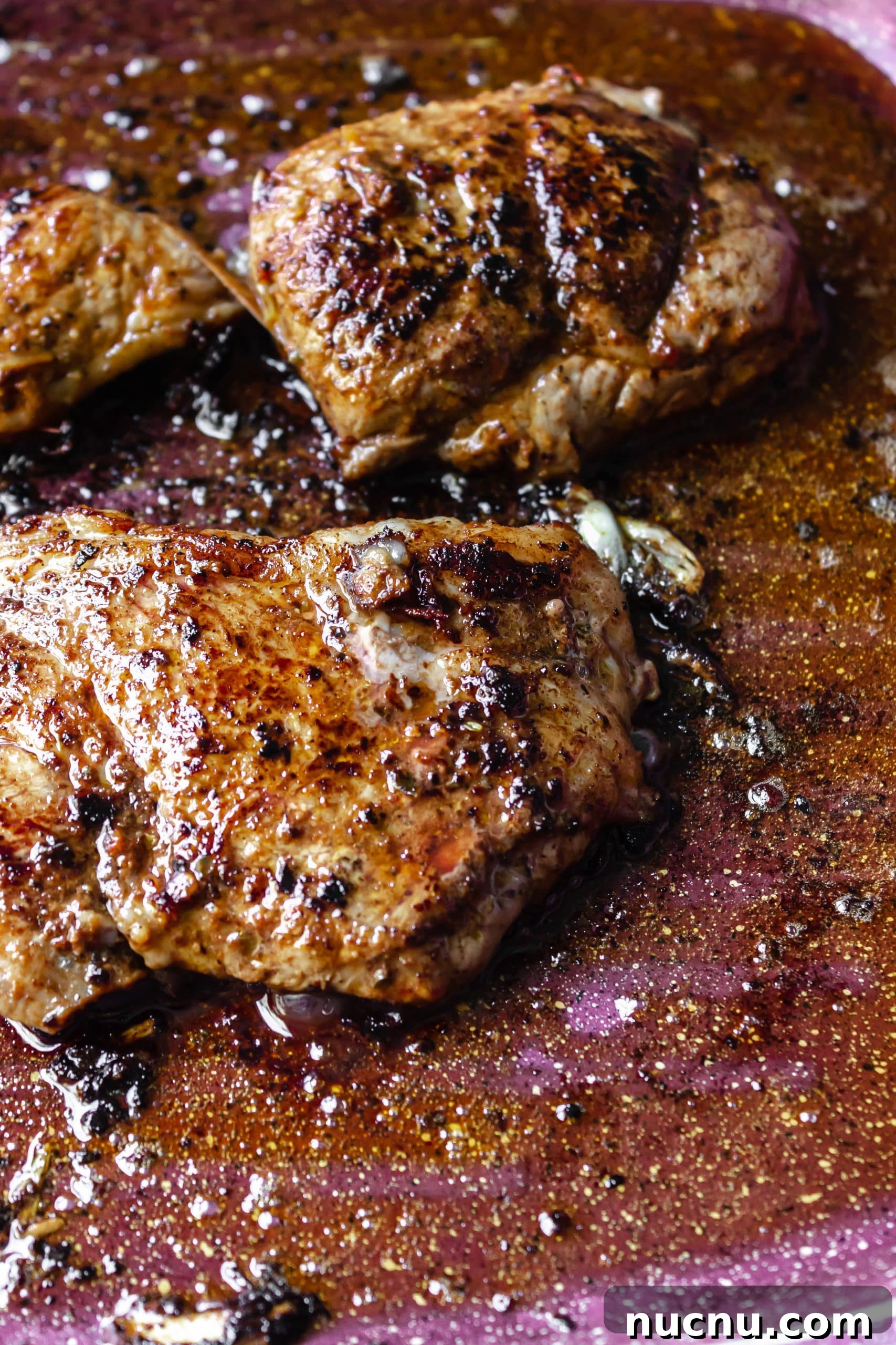 adobo sauce marinated steaks cooking in a large skillet