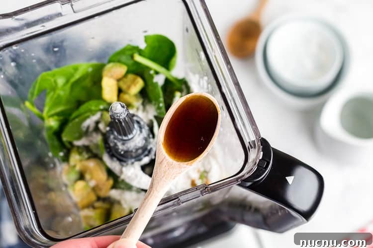 Keto Green Smoothie Vanilla Ice Cream Recipe for Low-Carb Desserts 4 overhead view of spoon with vanilla extract over keto green smoothie ingredients in a blender