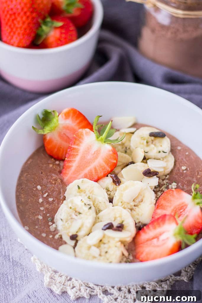 Healthy chocolate oatmeal porridge topped with banana and fresh strawberries