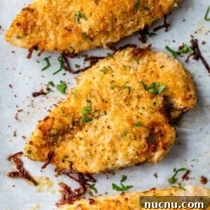 Crispy Baked Parmesan Chicken with Garlic and Herbs 7 baked parmesan chicken breasts on a baking sheet