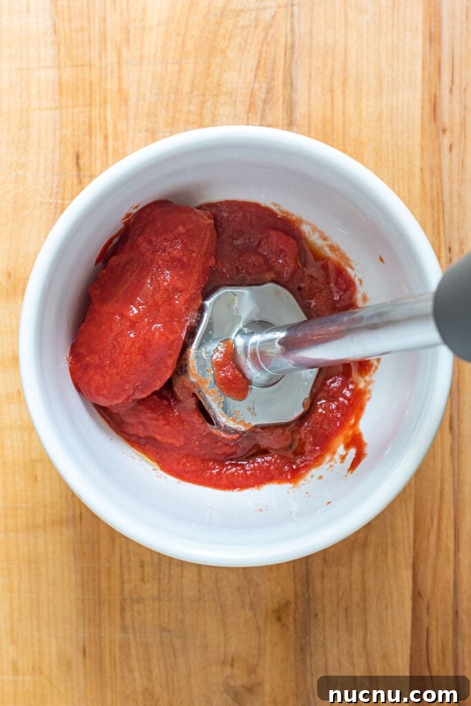 San Marzano tomatoes being blended with an immersion blender.