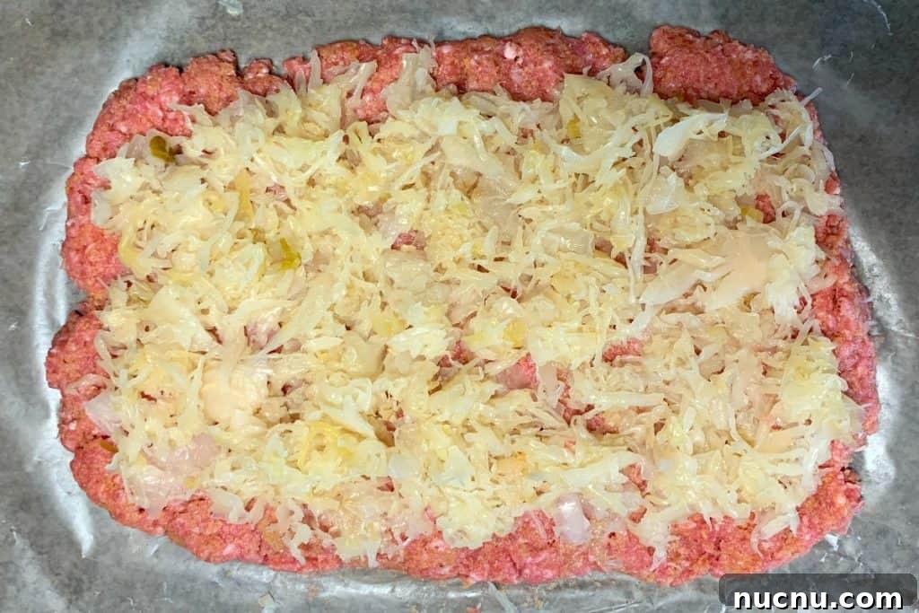 Raw ground pork mixture patted into rectangle on waxed paper and topped with sauerkraut and onion mixture