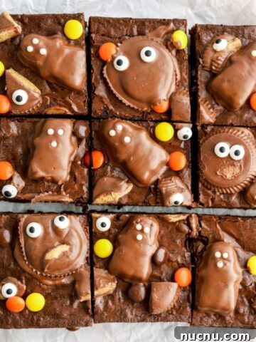 Brownies with monster faces made from peanut butter cups on top cut into slices.