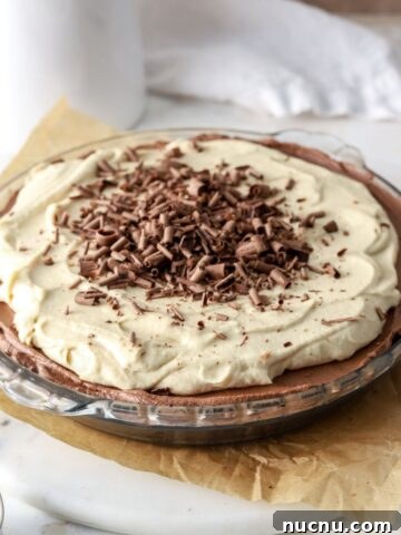 Chocolate pie with peanut butter whipped cream and chocolate shavings in a glass pie plate.