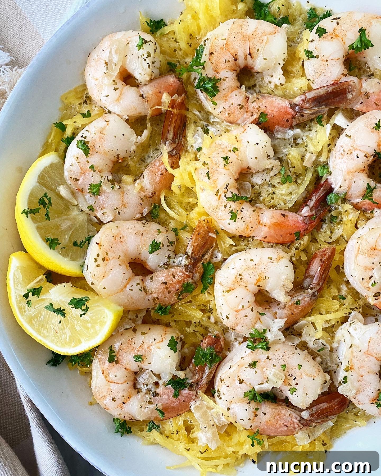 spaghetti squash shrimp scampi on a white plate with lemon slices