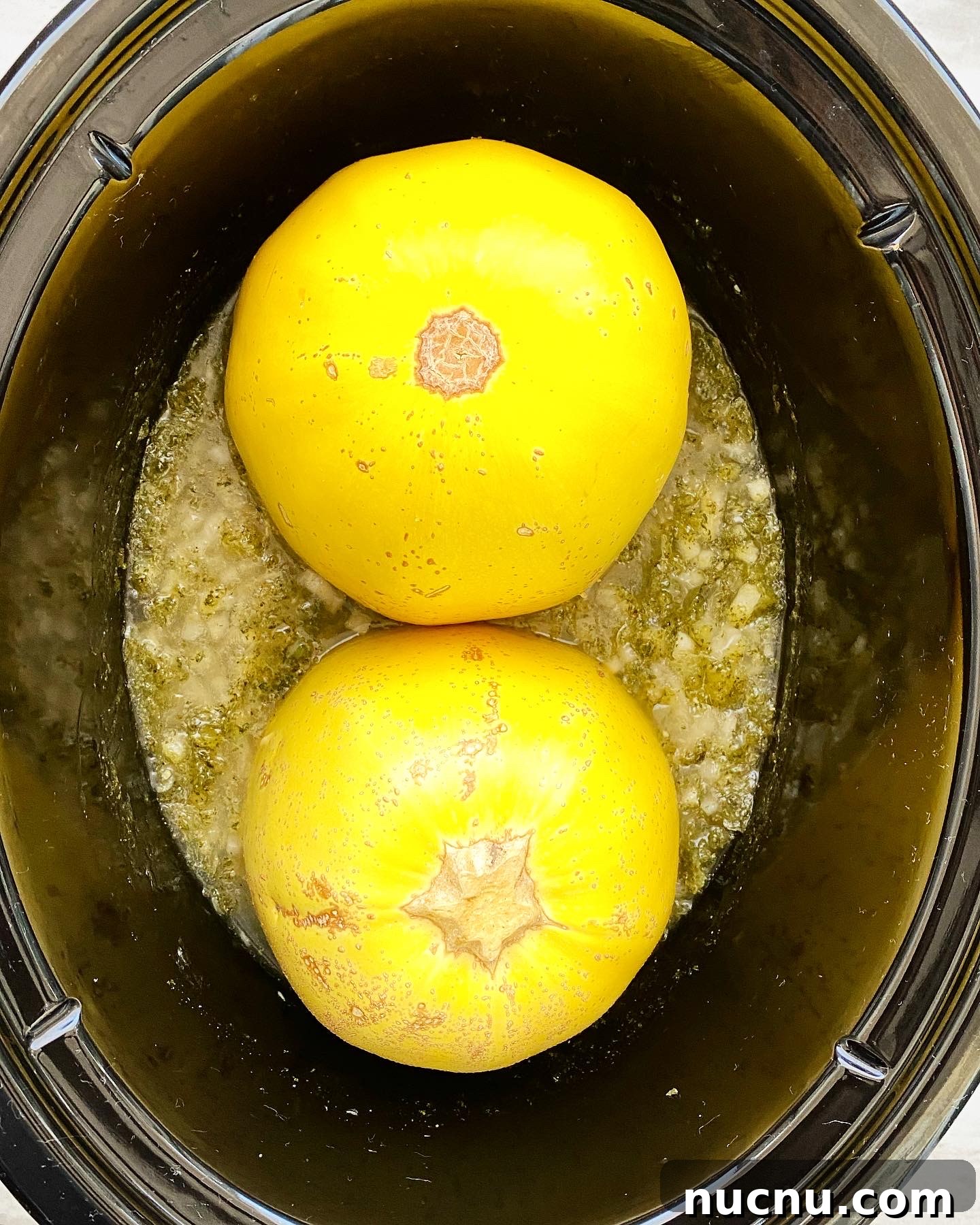 overhead shot of uncooked spaghetti squash in a black slow cooker