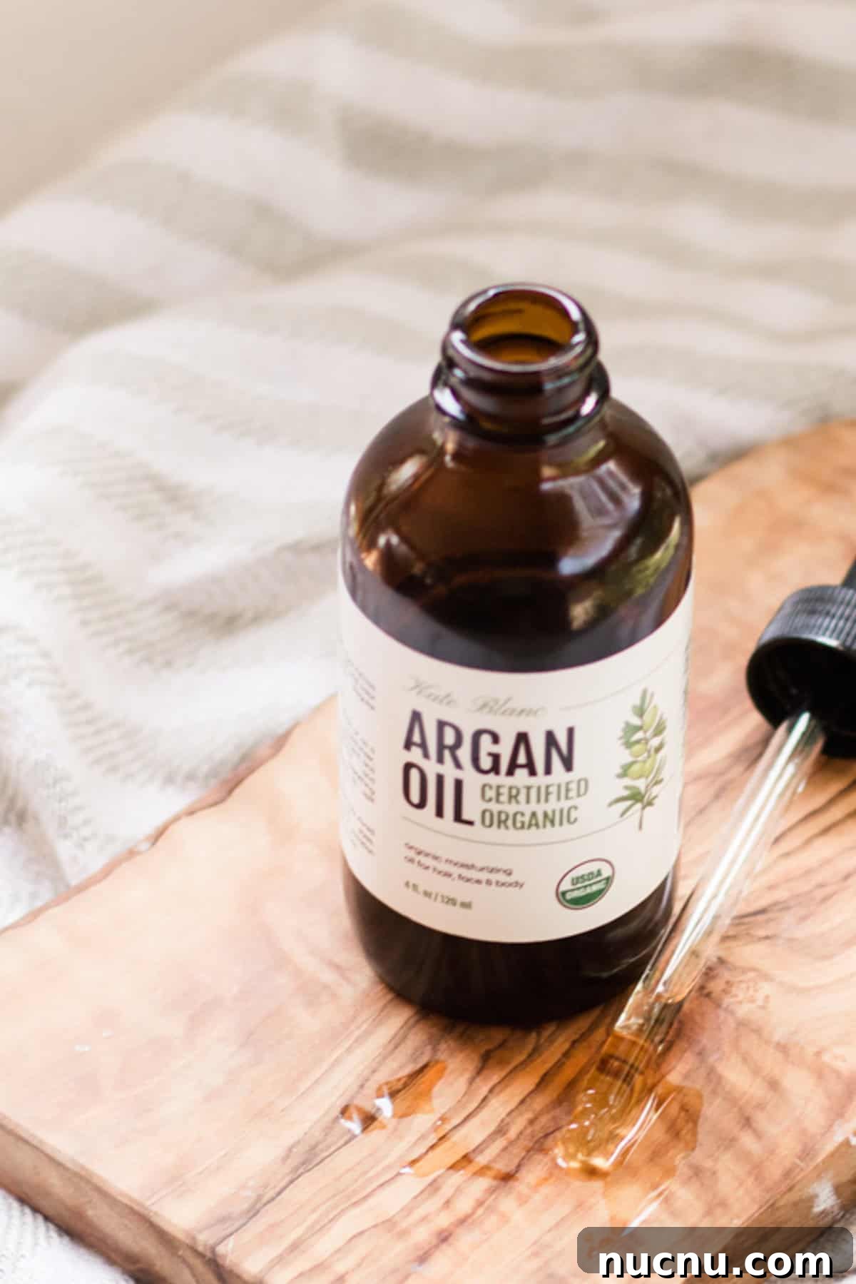 Make Your Own Argan Oil Face Serum: Hair and Skin Benefits 3 Amber glass bottle of argan oil on wooden board.