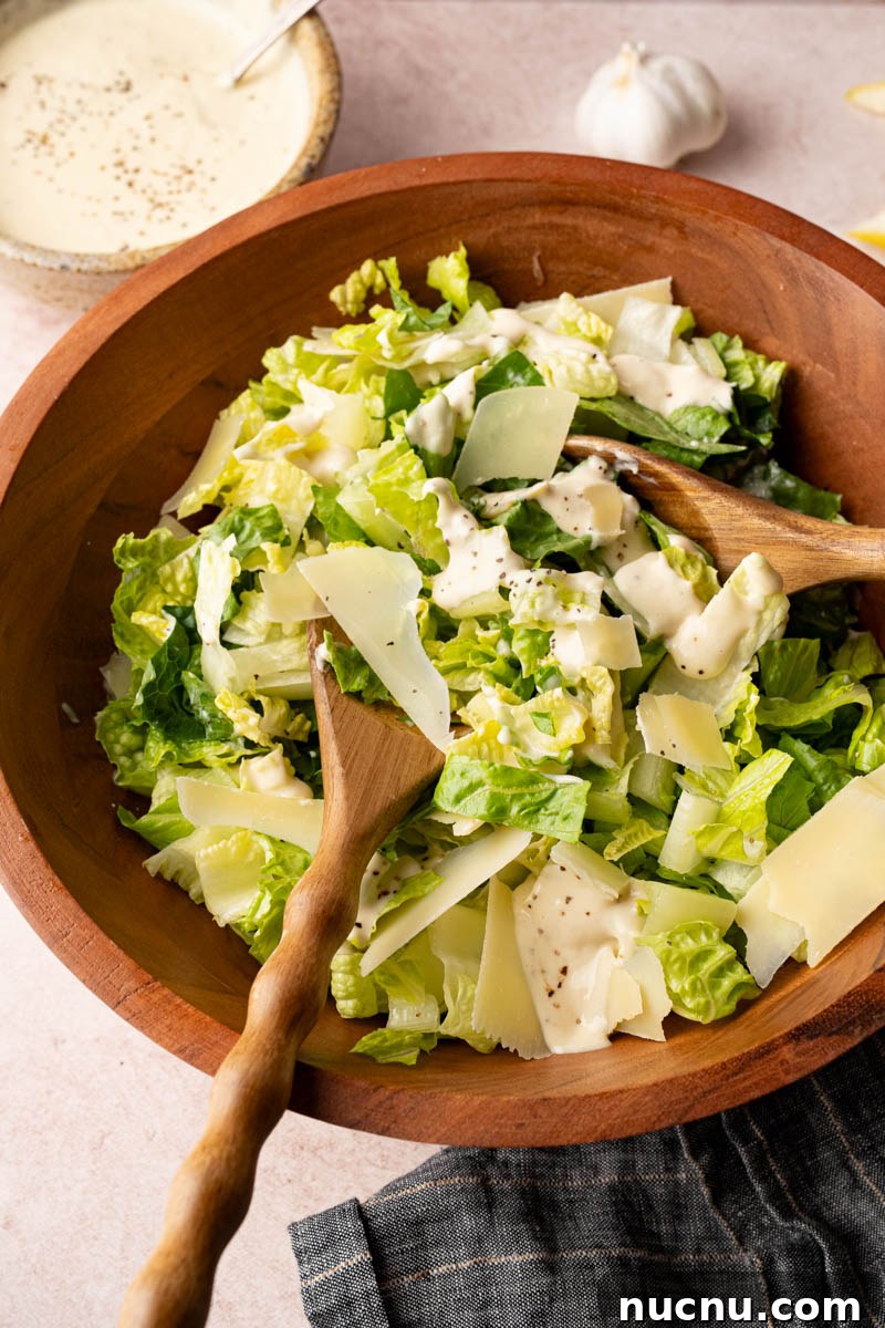 Classic Caesar Salad with Creamy Homemade Dressing and Croutons 5 Tossing together the romaine lettuce, parmesan cheese and homemade caesar dressing in a wooden bowl before serving.