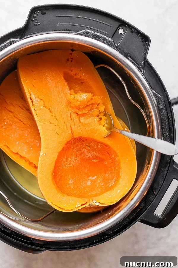 A spoon beginning to scoop the butternut squash meat out of the skin.