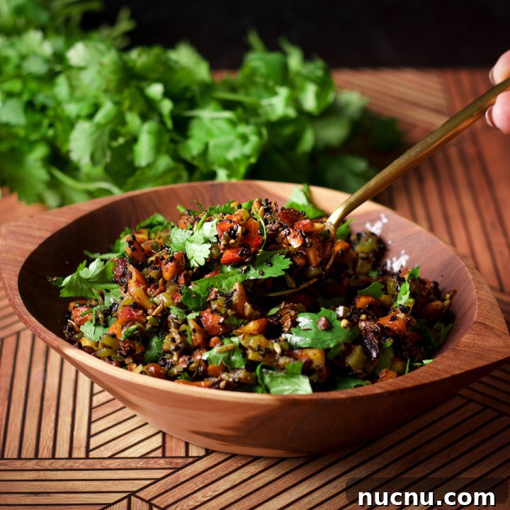 Someone lifting a spoonful of almond salsa from a wood bowl that's filled with the salsa.