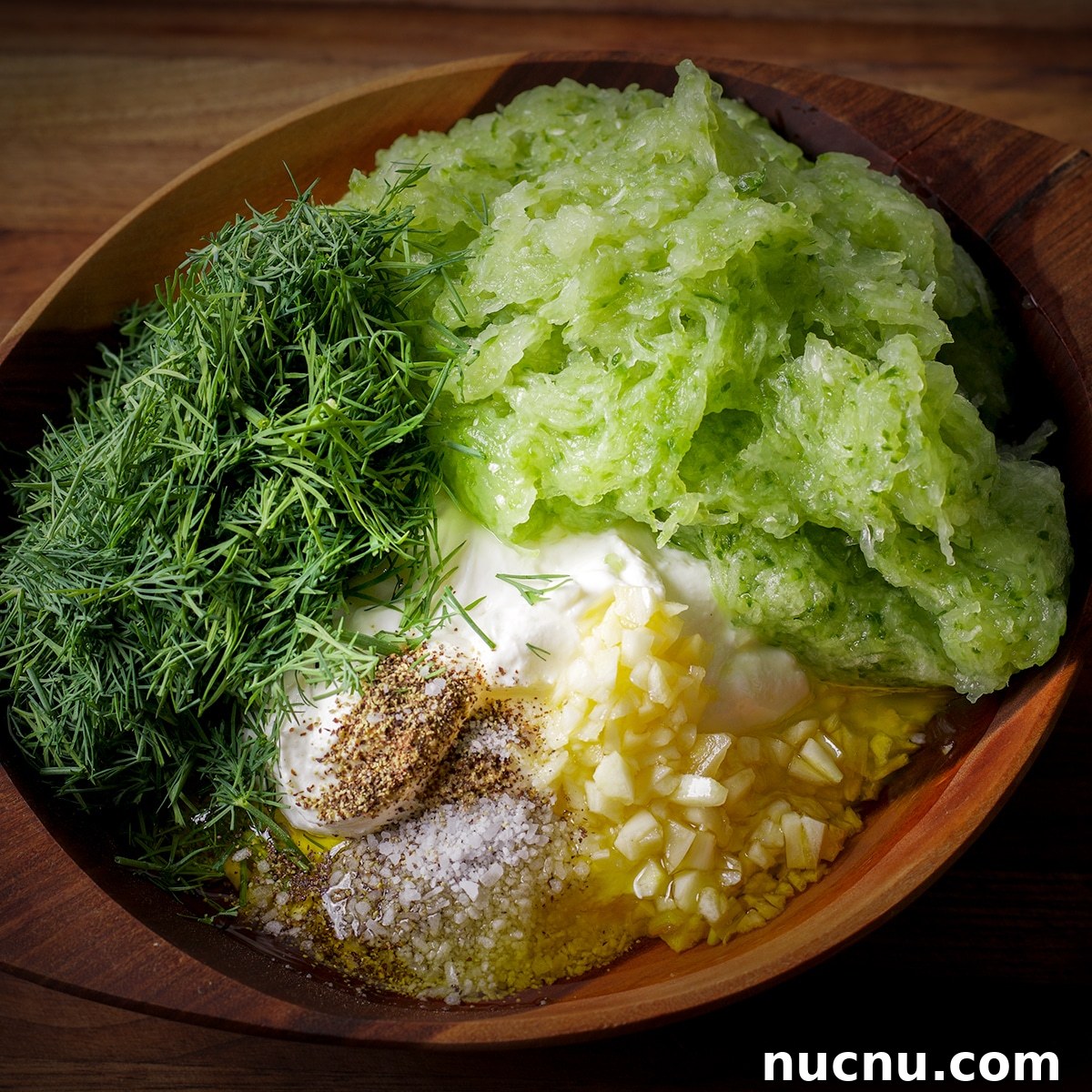 Traditional and Vegan Tzatziki: Authentic Recipes for Both Versions 6 A wood bowl containing all the ingredients to make tzatziki sauce before the sauce is mixed.