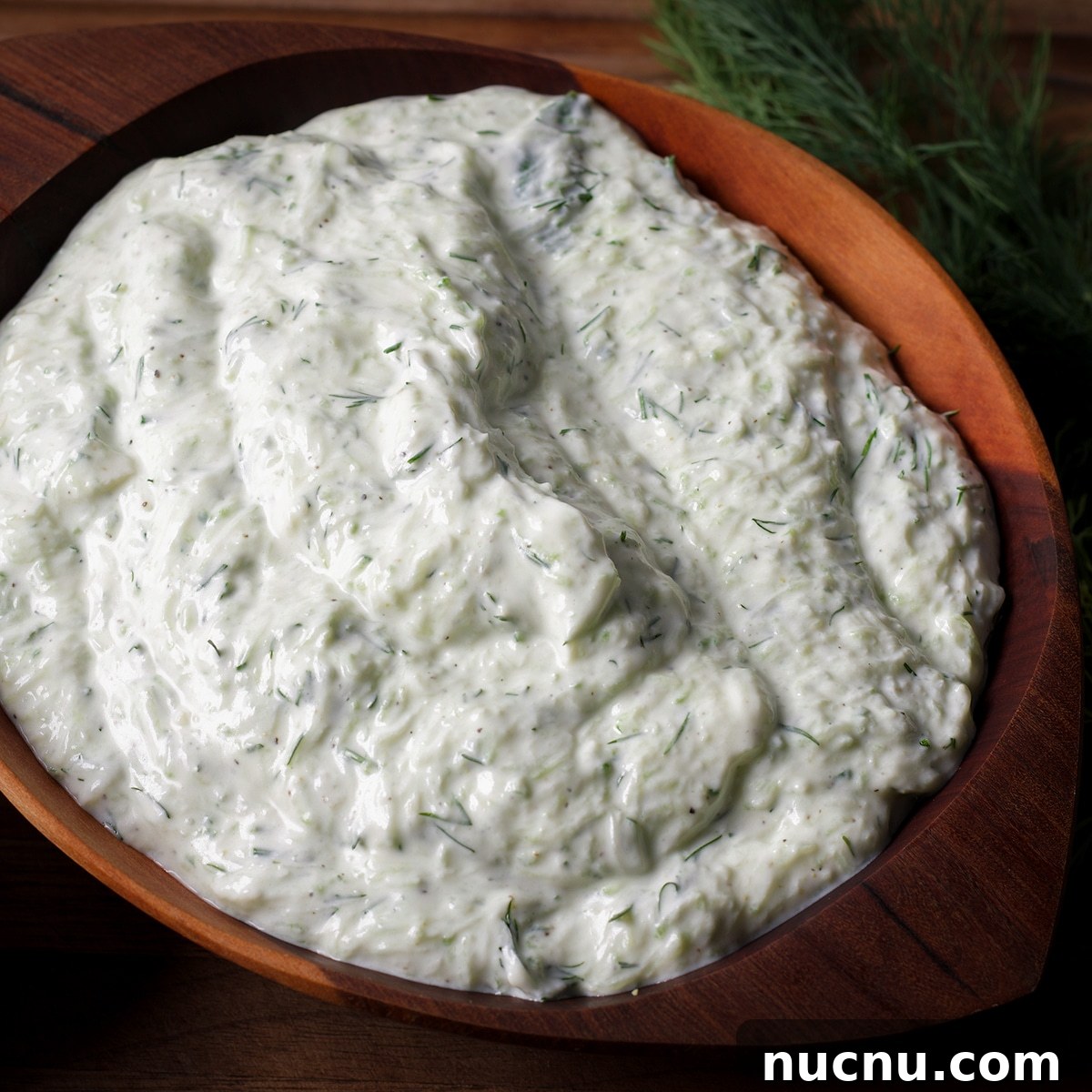 Traditional and Vegan Tzatziki: Authentic Recipes for Both Versions 7 A wood bowl containing homemade tzatziki sauce.