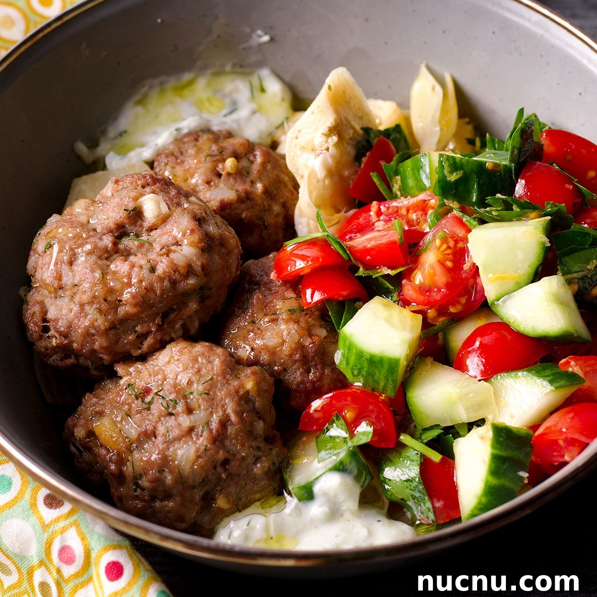 Traditional and Vegan Tzatziki: Authentic Recipes for Both Versions 10 A bowl containing Greek meatballs and tzatziki sauce, and tomato and cucumber salad.