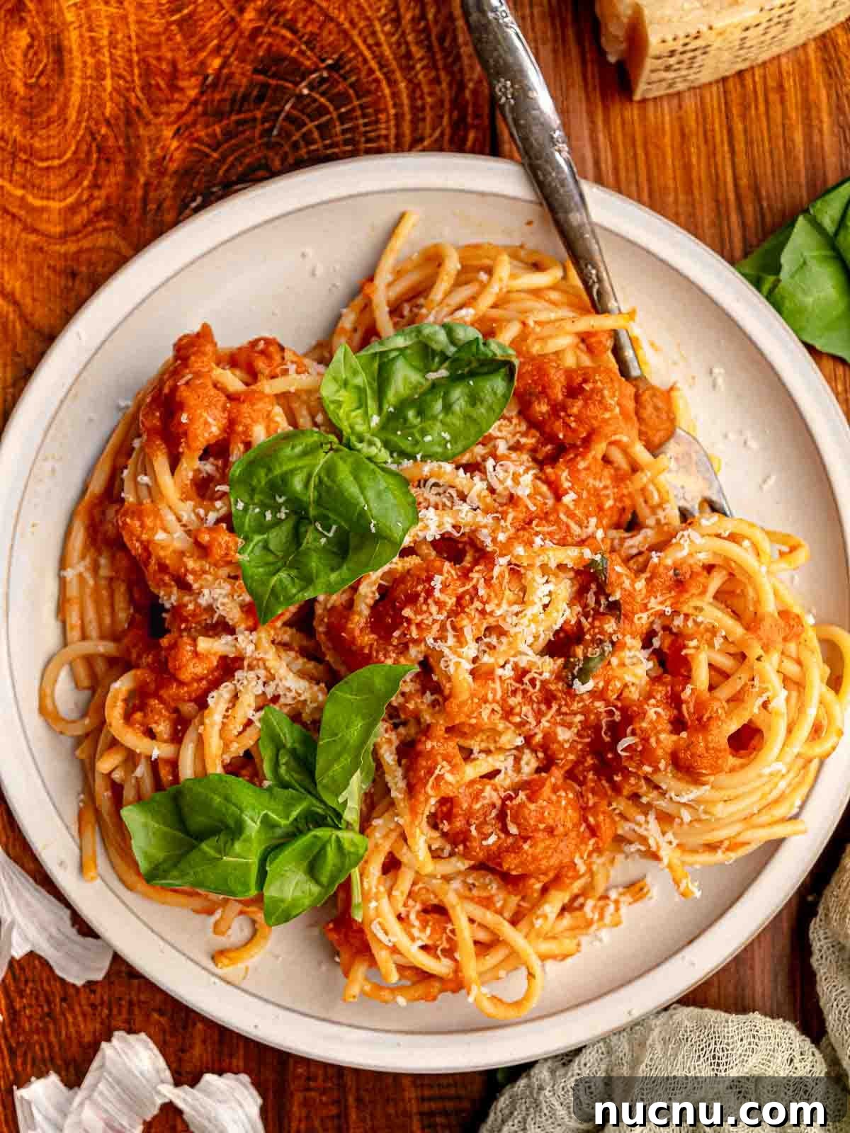 A plate of spaghetti with red sauce and basil.