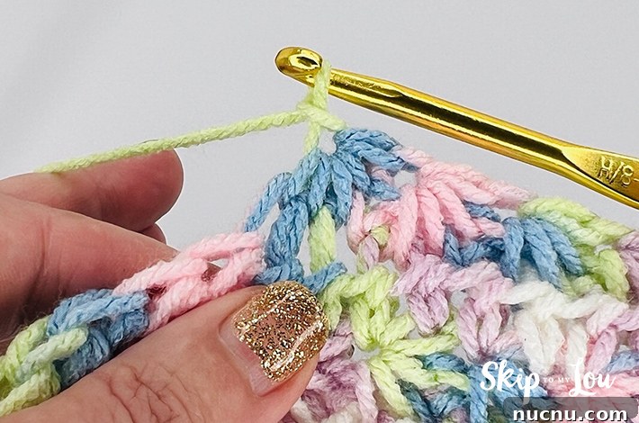 A multicolored yarn in yellow, blue, pink, purple, and white in a star stitch pattern.