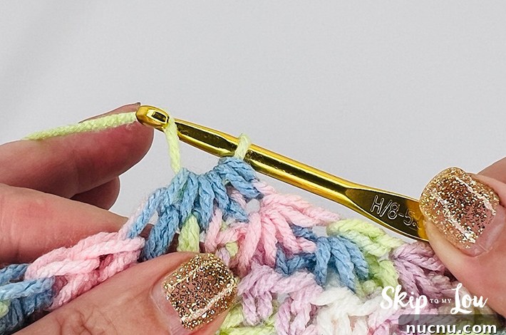 A multicolored yarn in yellow, blue, pink, purple, and white in a star stitch pattern.