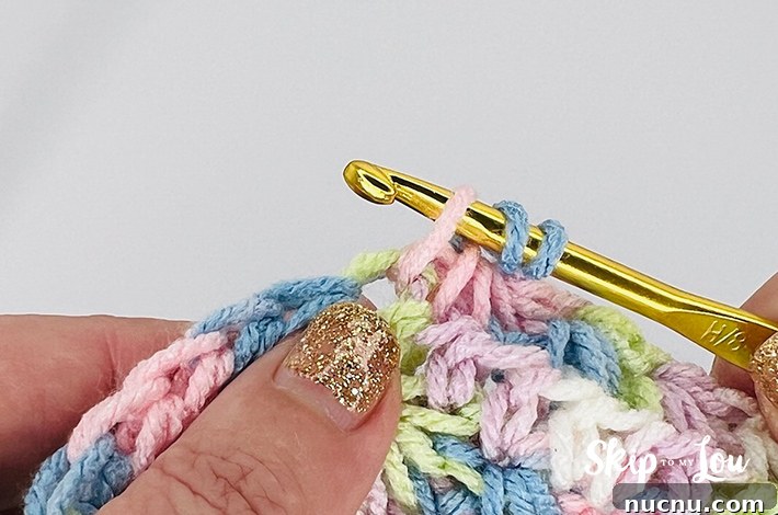 A multicolored yarn in yellow, blue, pink, purple, and white in a star stitch pattern.