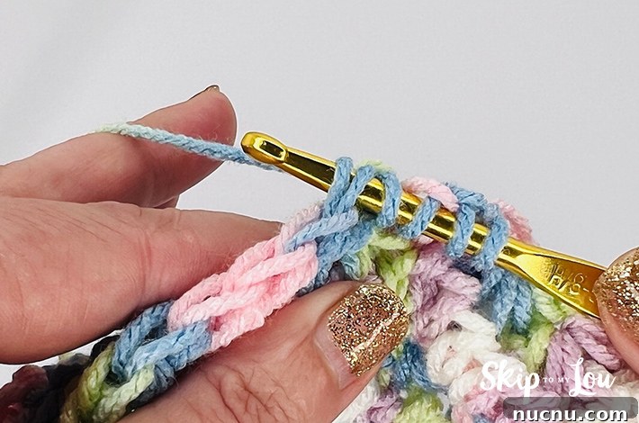 A multicolored yarn in yellow, blue, pink, purple, and white in a star stitch pattern.