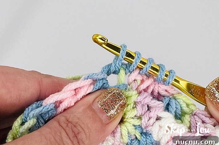 A multicolored yarn in yellow, blue, pink, purple, and white in a star stitch pattern.