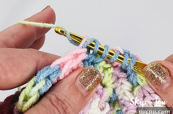 A multicolored yarn in yellow, blue, pink, purple, and white in a star stitch pattern.