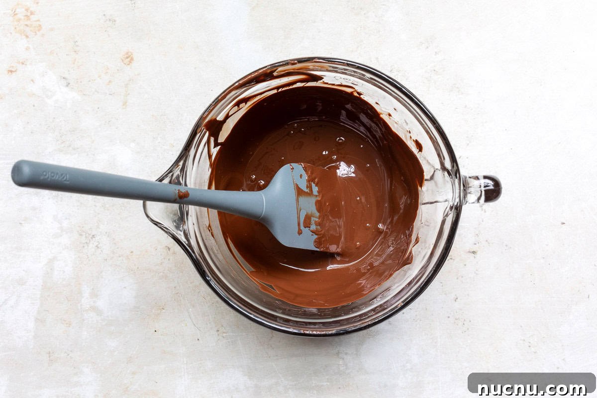 Decadent Homemade Chocolate Mousse Recipe for Silky Results 5 melted chocolate in bowl with spatula.