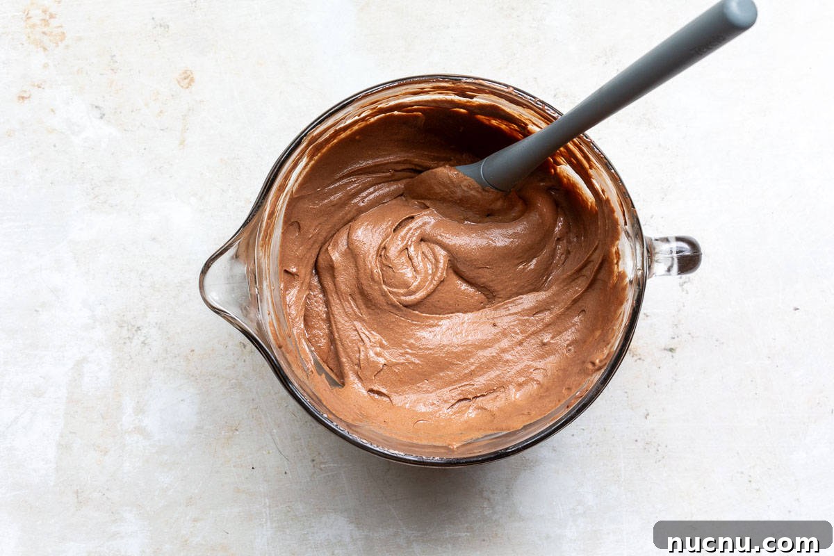 Decadent Homemade Chocolate Mousse Recipe for Silky Results 9 chocolate mousse batter in mixing bowl with spatula.
