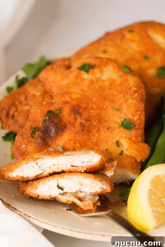 a crispy chicken cutlet with some slices on a fork