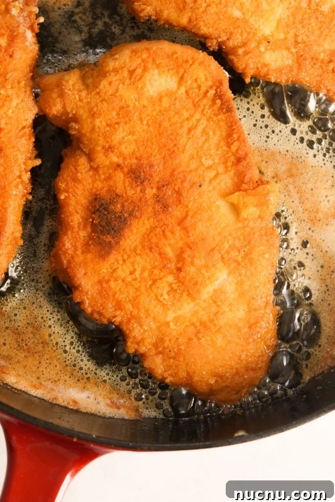crusted romano chicken in a pan with oil