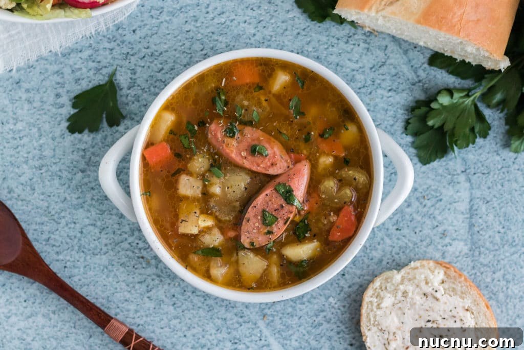 An overhead image of Bavarian Potato Soup with two diagonally sliced sausages on top