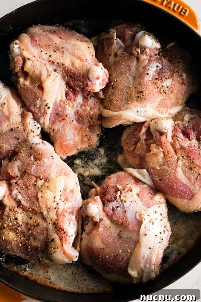 chicken thighs searing in a cast iron skillet
