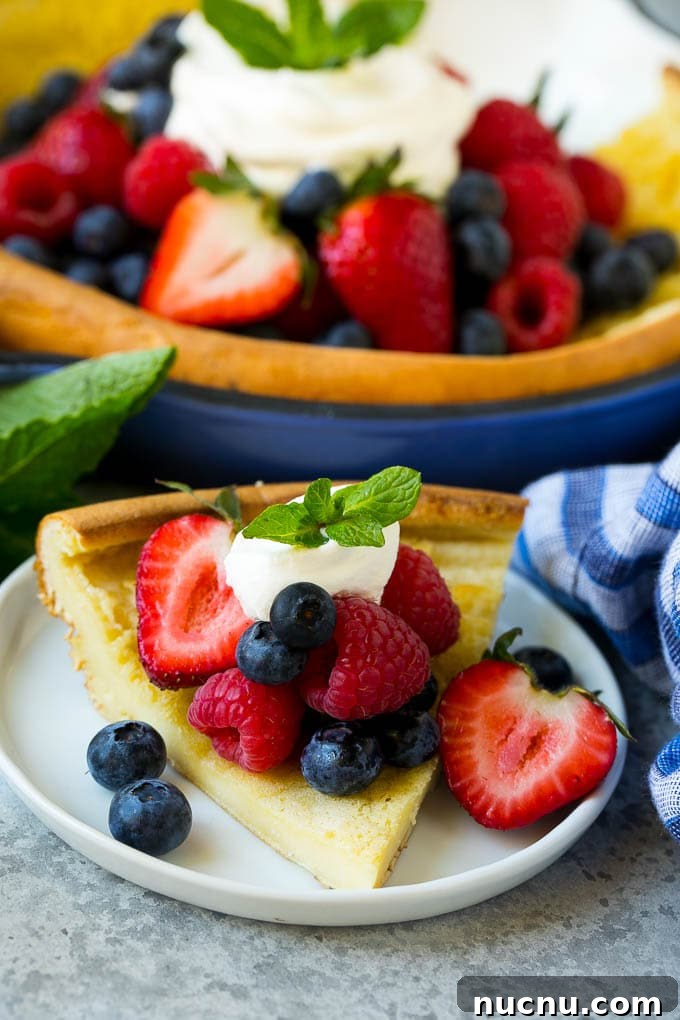 Served Dutch Baby A slice of Dutch baby pancake topped with berries and whipped cream.