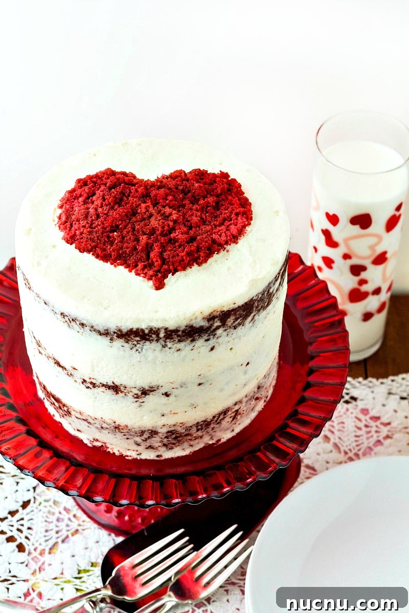 Red Velvet Cake with Silky Ermine Buttercream Frosting 2 3/4 view of tall stacked red velvet cake frosted in white with a red heart on top