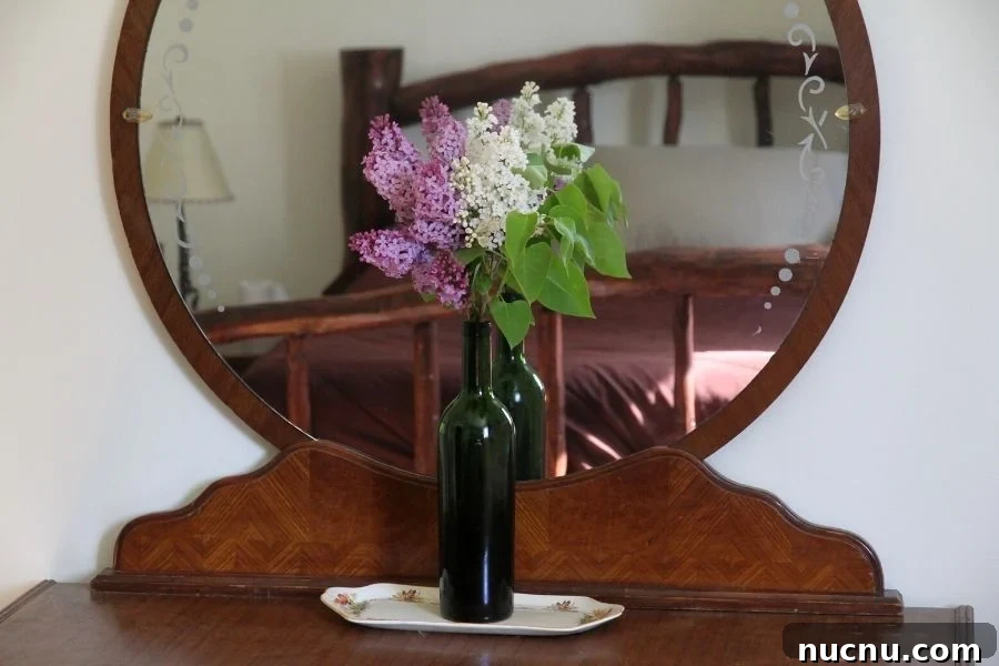 a green bottle filled with lavendar and white lilac blossoms