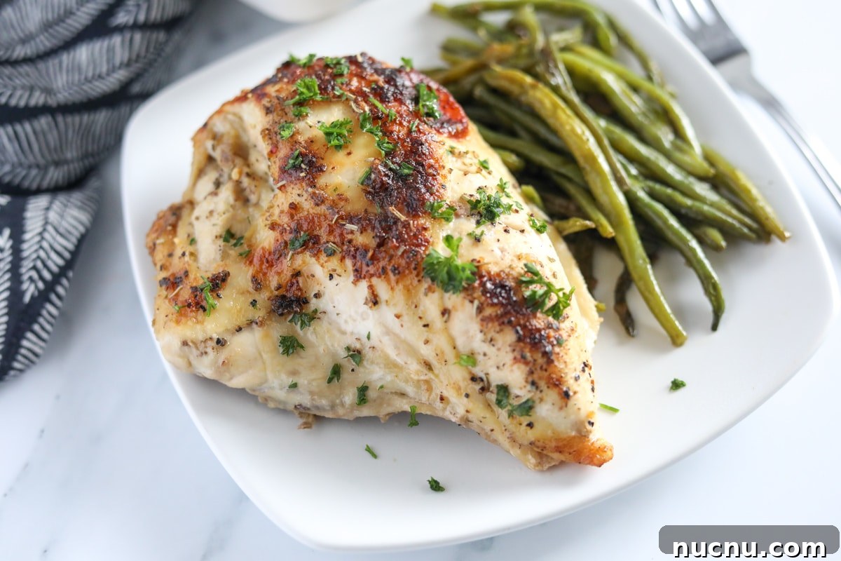 Zesty Italian Chicken and Classic Dressing Recipe 4 Baked italian chicken breast on a white plate with green beans on the side.