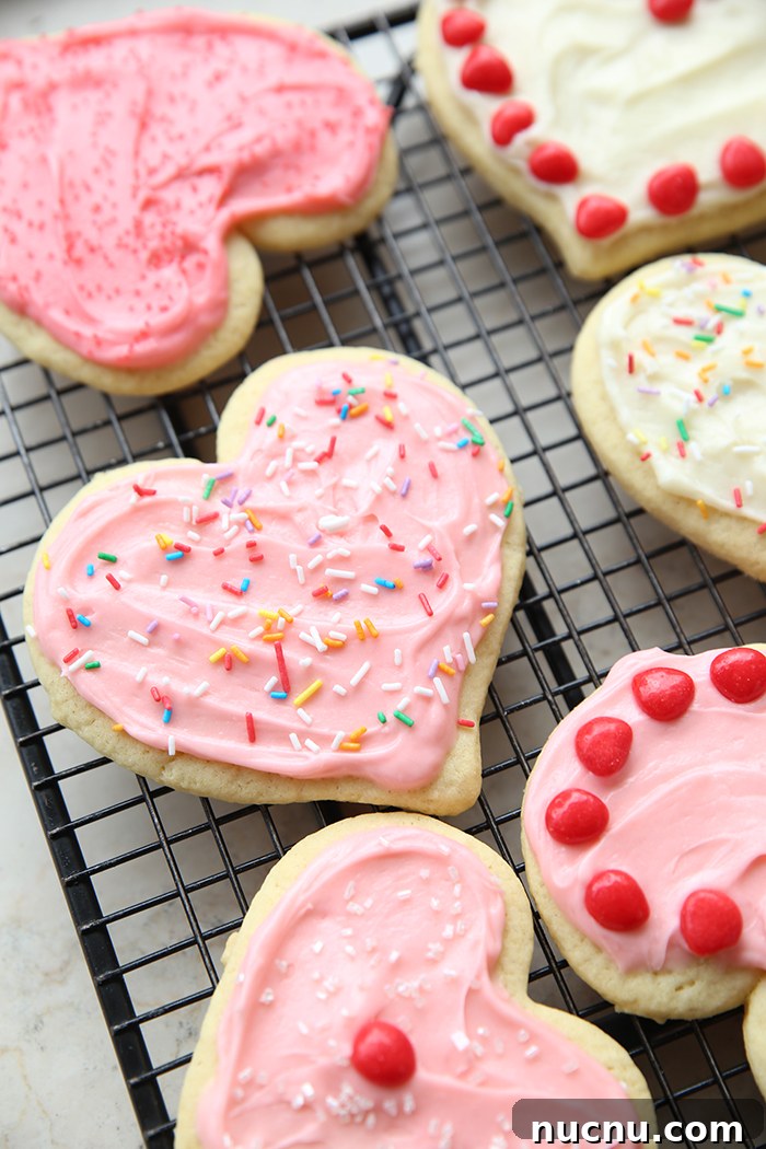 Six sugar cookies heart-shaped, frosted and decorated with Red Hots and sprinkles.