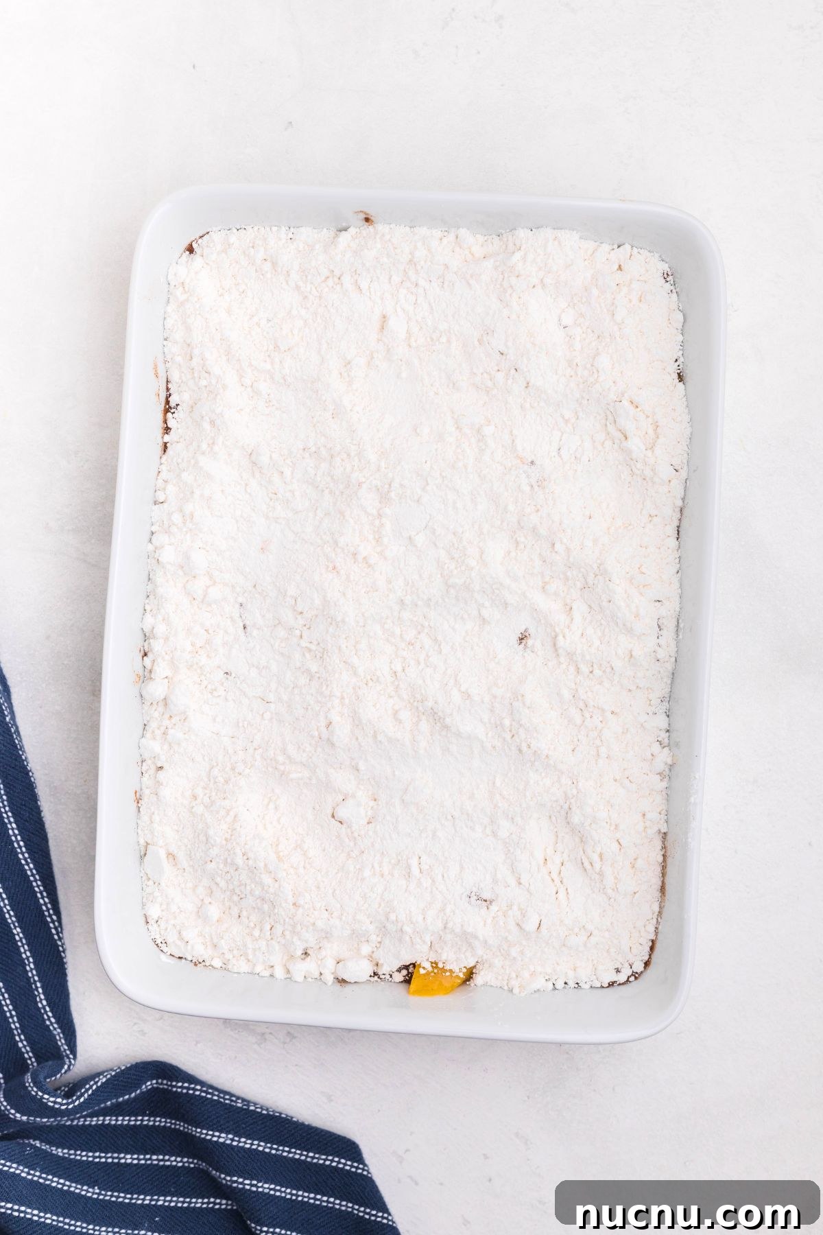 Irresistible Peach Dump Cake Recipe for Quick Summer Desserts 5 Cake mix powder, spread out over peaches, in a a white rectangle dish.