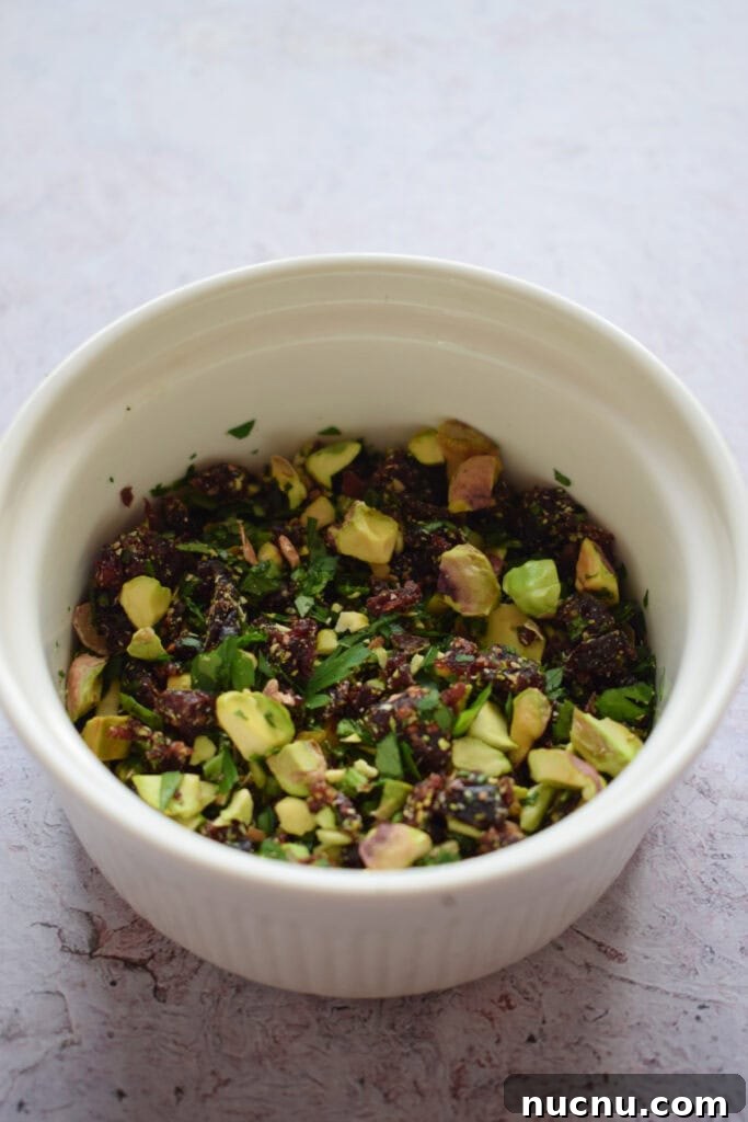 Cranberry Pistachio Goat Cheese Ball Recipe for Parties 12 Chopped nuts and cranberries in a white bowl.