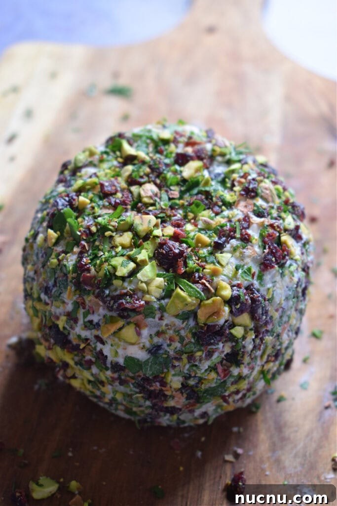 Cranberry Pistachio Goat Cheese Ball Recipe for Parties 14 Cranberry and Pistachio Goat cheese ball on a wooden board.