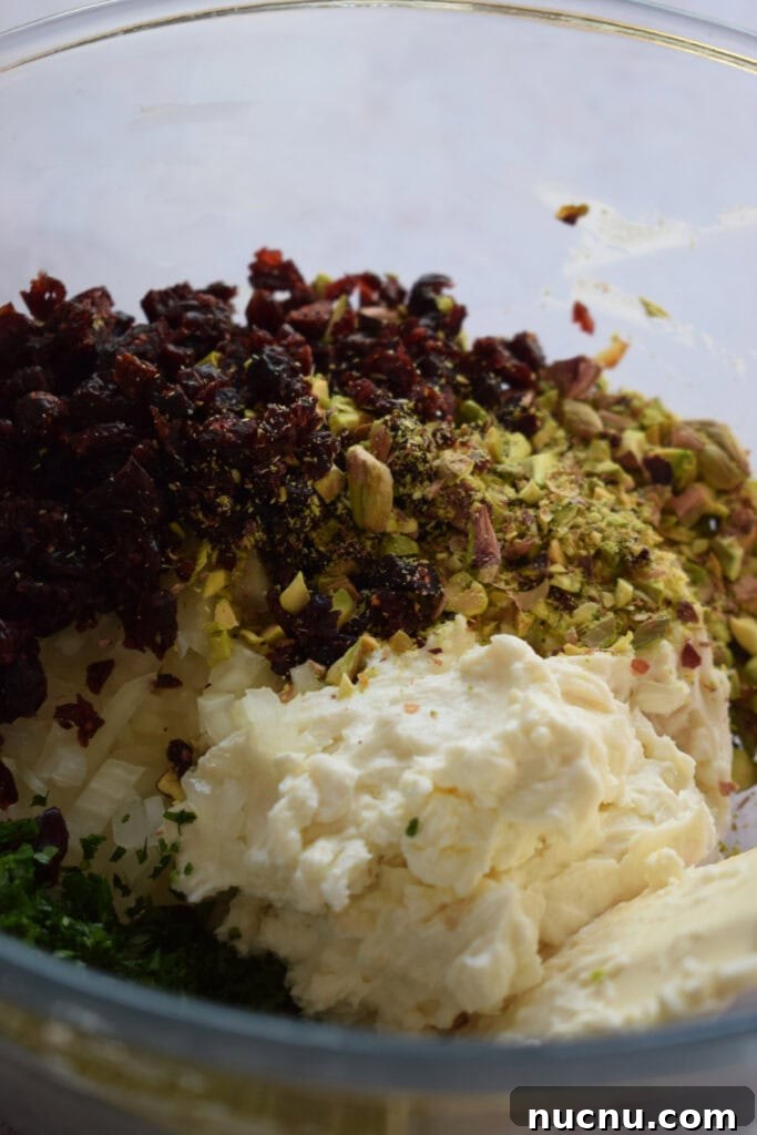 Cranberry Pistachio Goat Cheese Ball Recipe for Parties 8 Goat cheese with cranberries and nuts in a bowl.