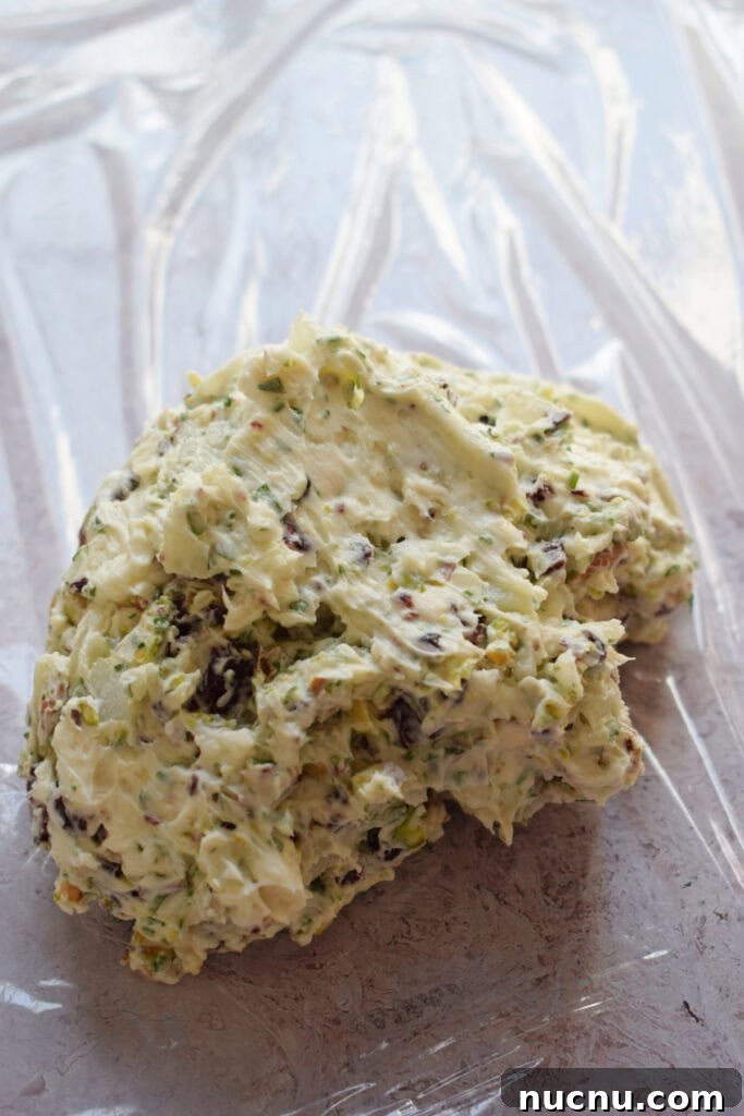 Cranberry Pistachio Goat Cheese Ball Recipe for Parties 10 Goat cheese filling on a sheet of plastic wrap.