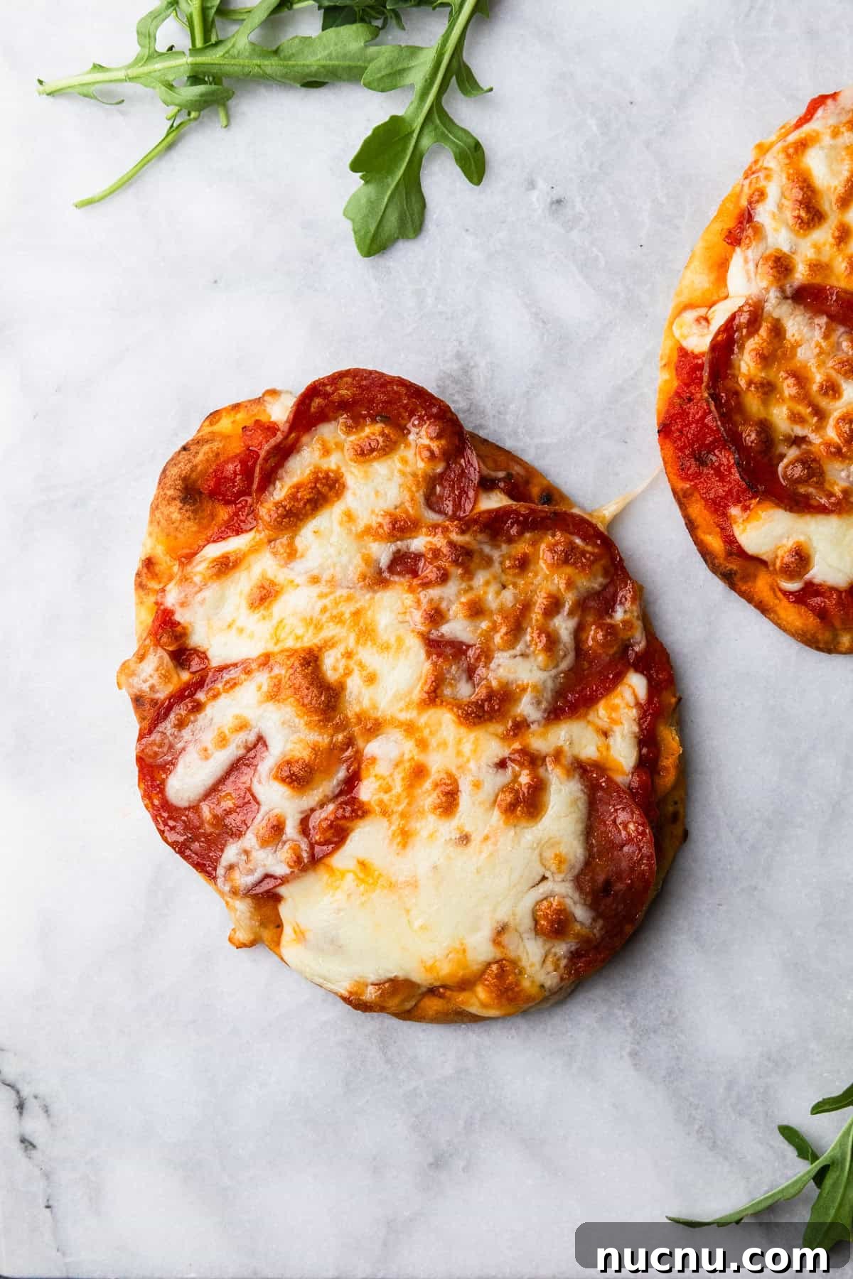 Crispy Air Fryer Naan Pizza Recipe for Quick Weeknight Meals 2 Air fryer naan pizza on a marble board.