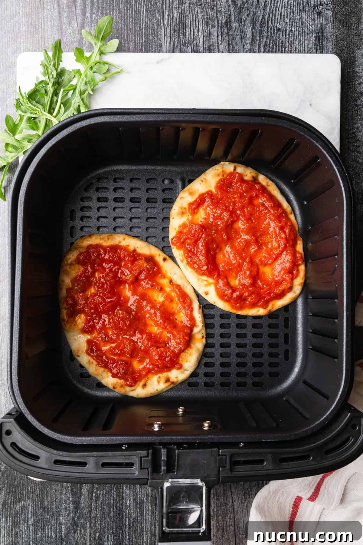 Crispy Air Fryer Naan Pizza Recipe for Quick Weeknight Meals 4 Naan bread in air fryer basket with pizza sauce.
