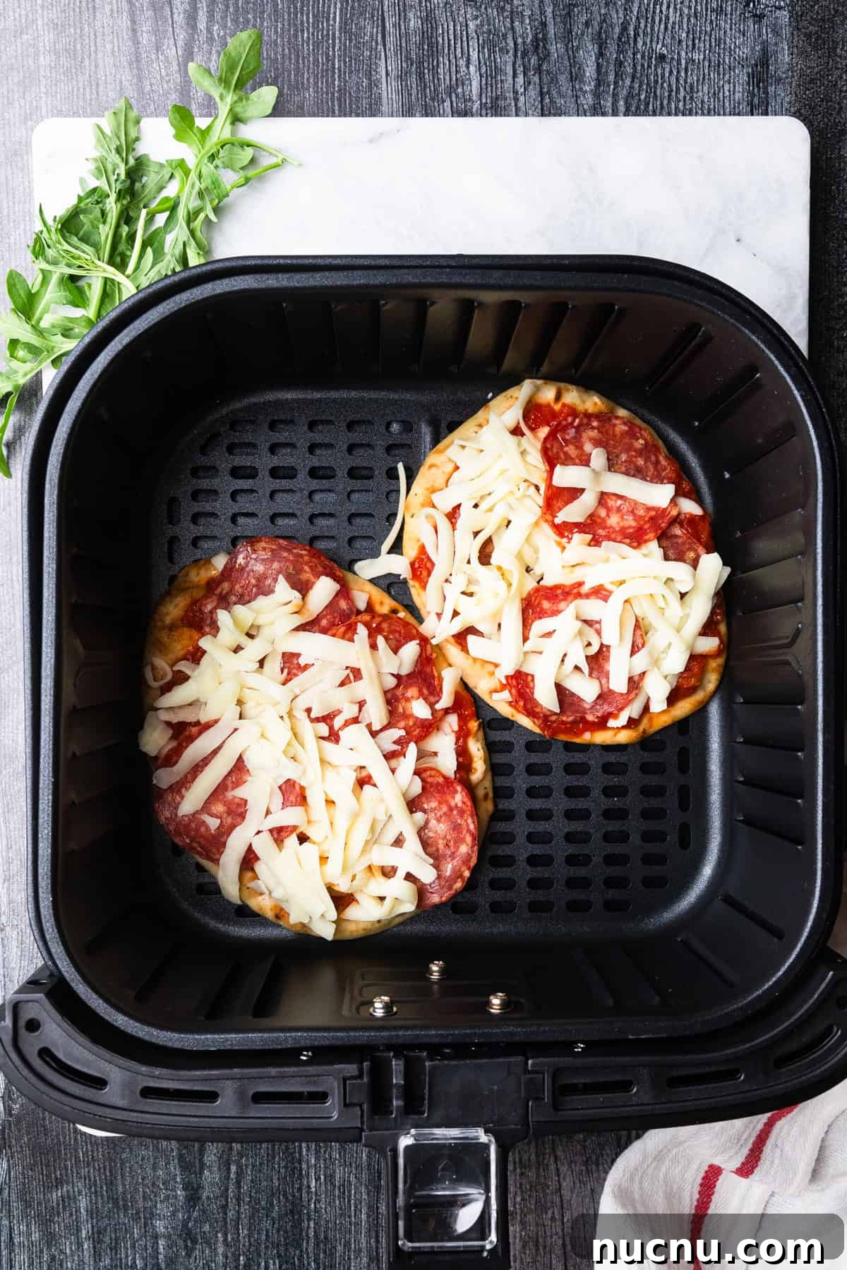 Crispy Air Fryer Naan Pizza Recipe for Quick Weeknight Meals 5 Adding cheese to top of sauce of pizza.