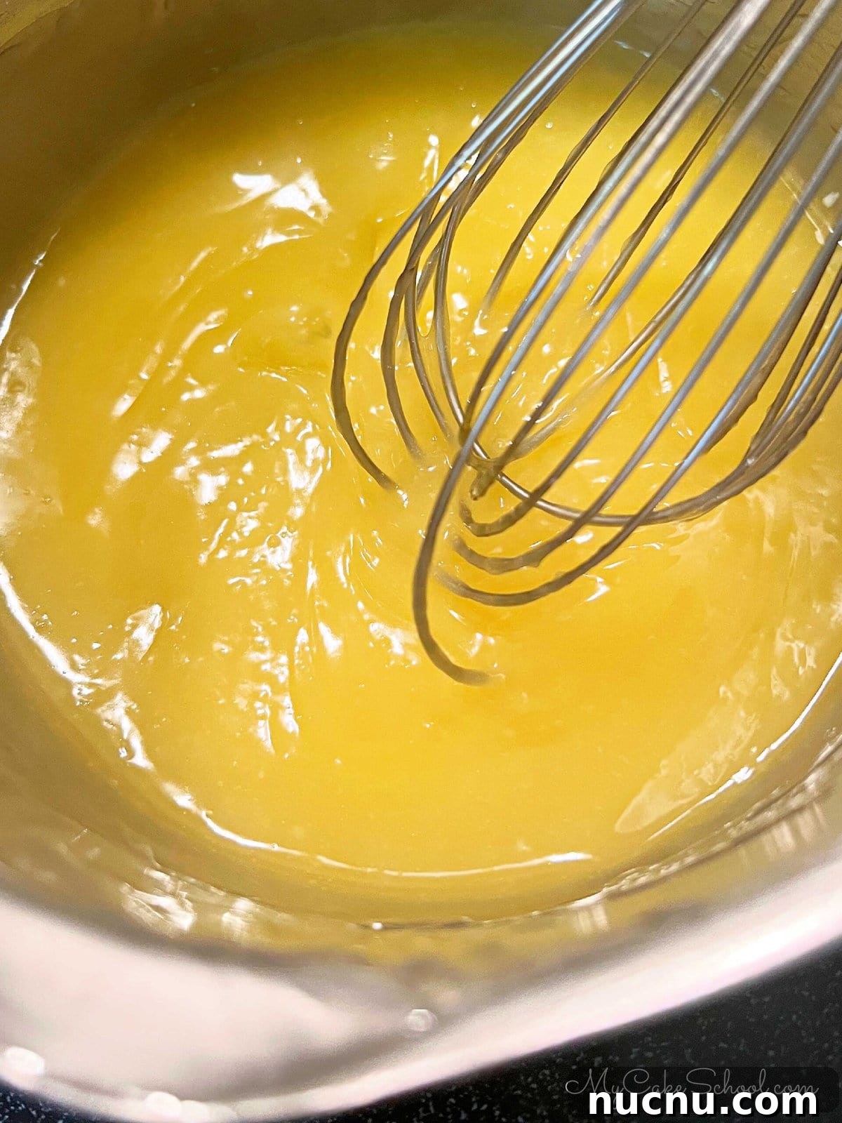 Lemon and Orange Layer Cake Recipe for Zesty Citrus Dessert 3 Preparing orange curd in a saucepan with a whisk.